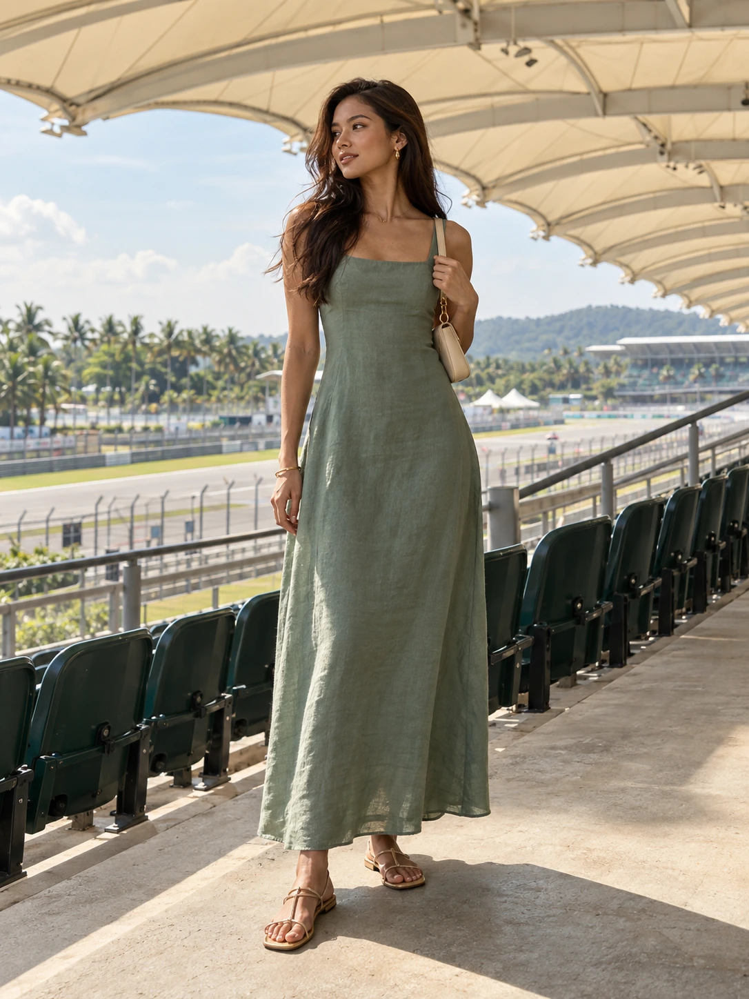 A woman in a muted jade maxi tank dress and secure flat sandals in grandstand shade.
