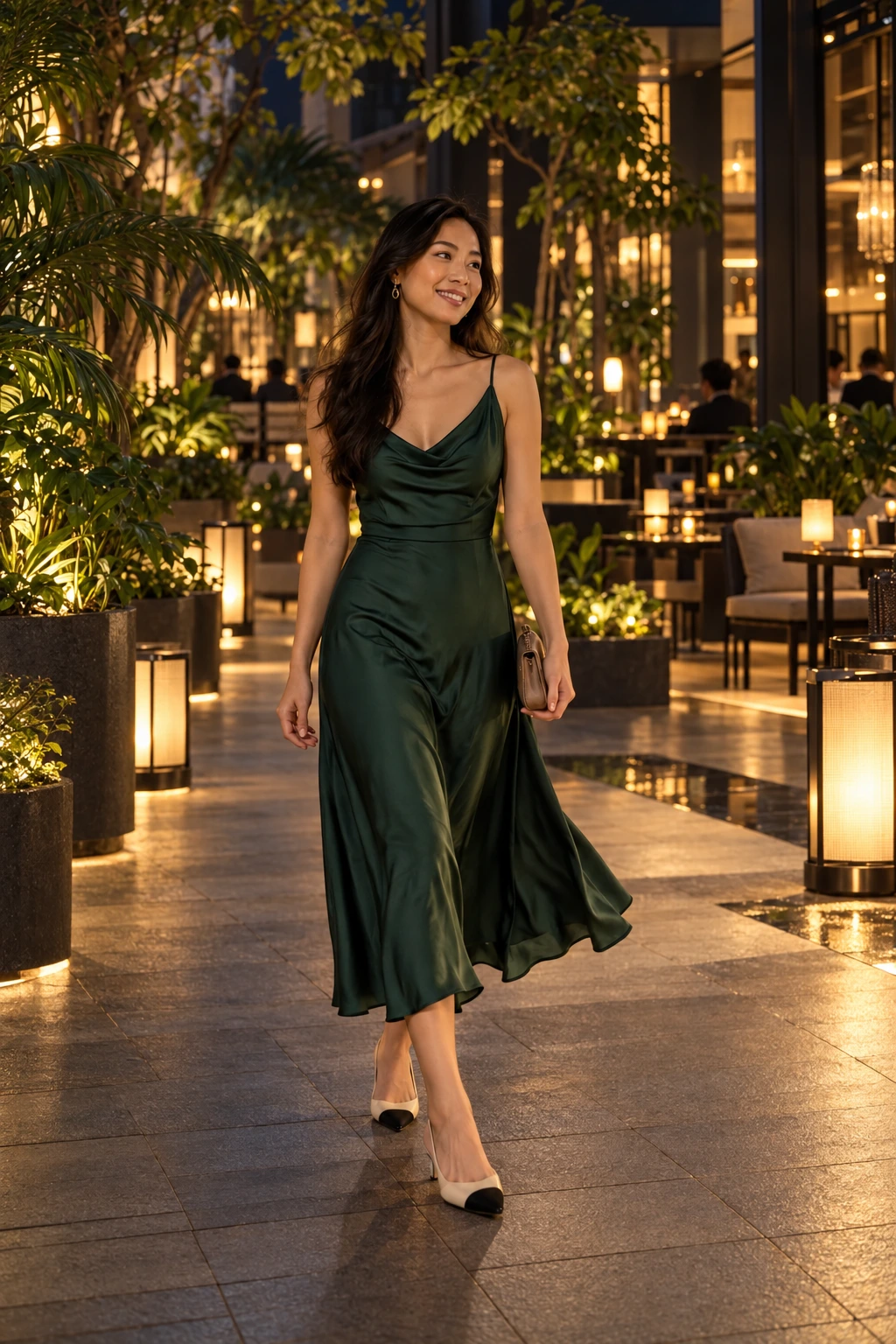 A woman in a deep jade fluid midi dress and secure low shoes in a warmly lit tropical hospitality courtyard after dark.